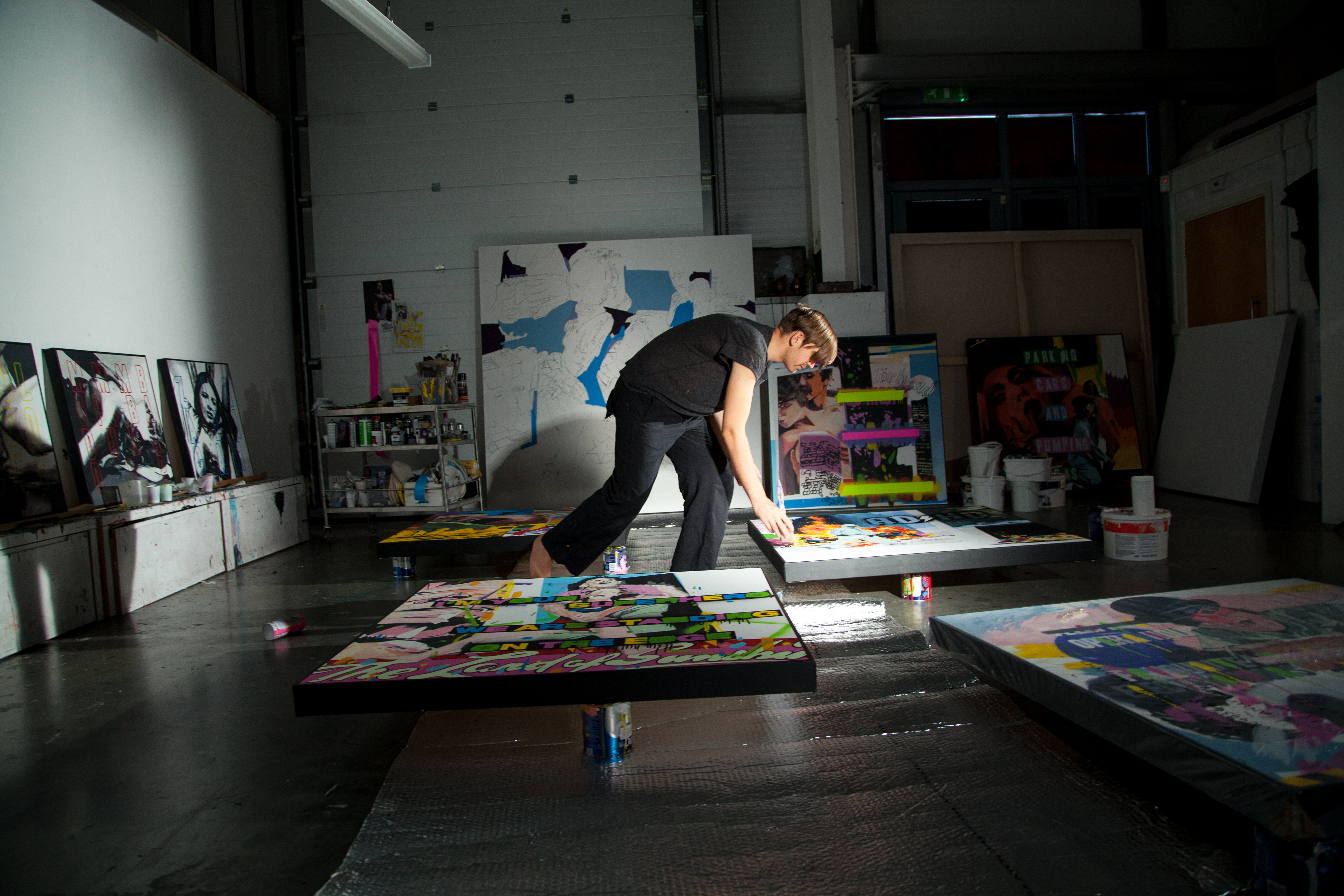 Stuart Semple paints a canvas barefoot in a studio space